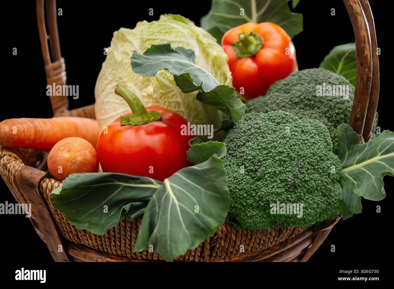 Un cestino pieno di verdure fresche, tra cui lattuga, peperoni, broccoli e carote, perfetto per pasti o presentazioni. Foto Stock