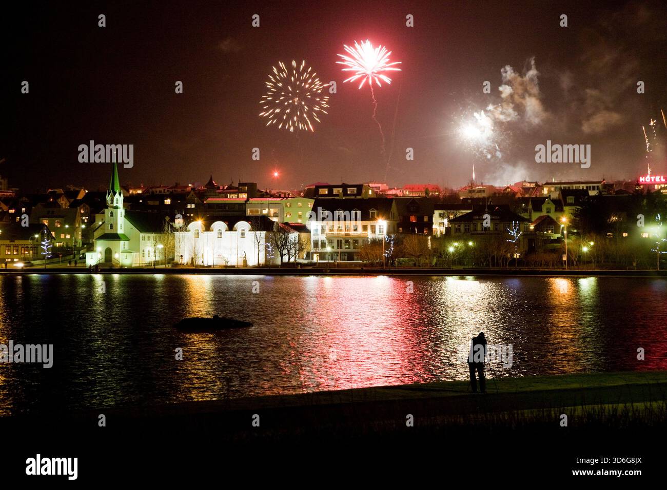 Fuochi d'artificio la vigilia di Capodanno a mezzanotte. Lago Tjornin, centro di Reykjavik, Islanda. Foto Stock