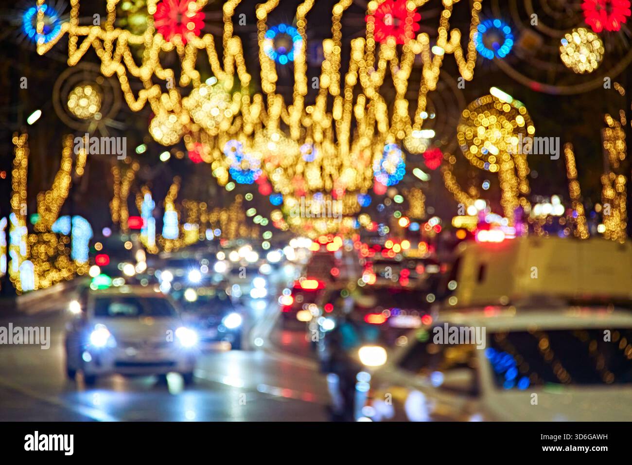 Sfondo urbano astratto e sfocato di ingorghi notturni con decorazioni natalizie brillanti, luci bokeh e un'atmosfera frenetica della città. Foto Stock