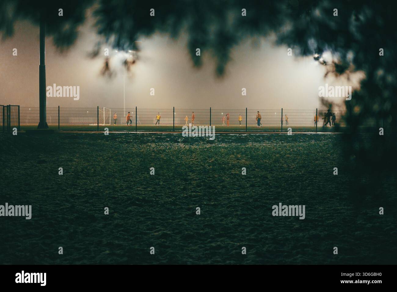 Scena notturna di campi da calcio con giocatori in autunno, atmosfera nebbiosa. Foto Stock