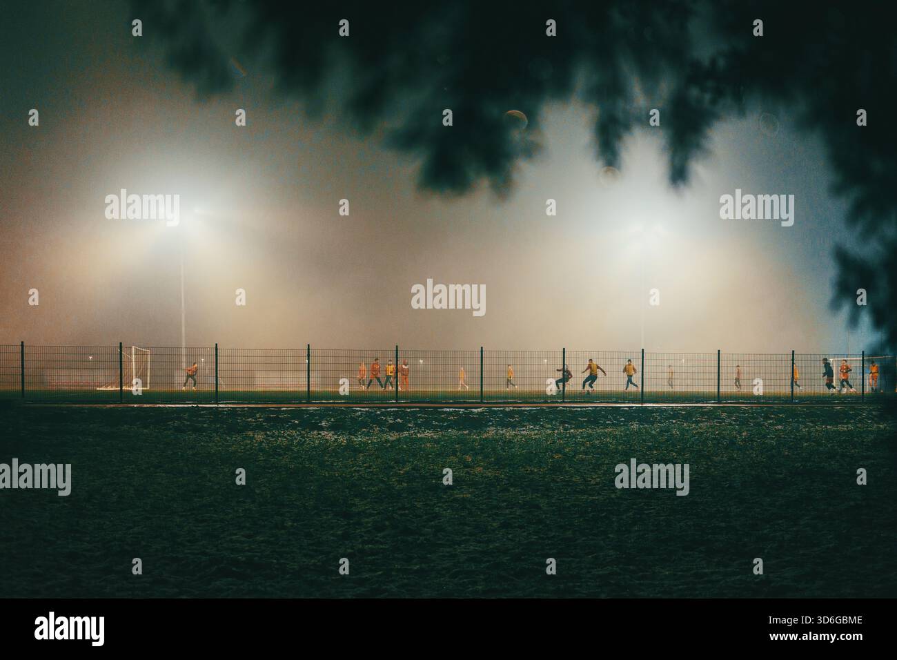 Scena notturna di campi da calcio con giocatori in autunno, atmosfera nebbiosa. Foto Stock