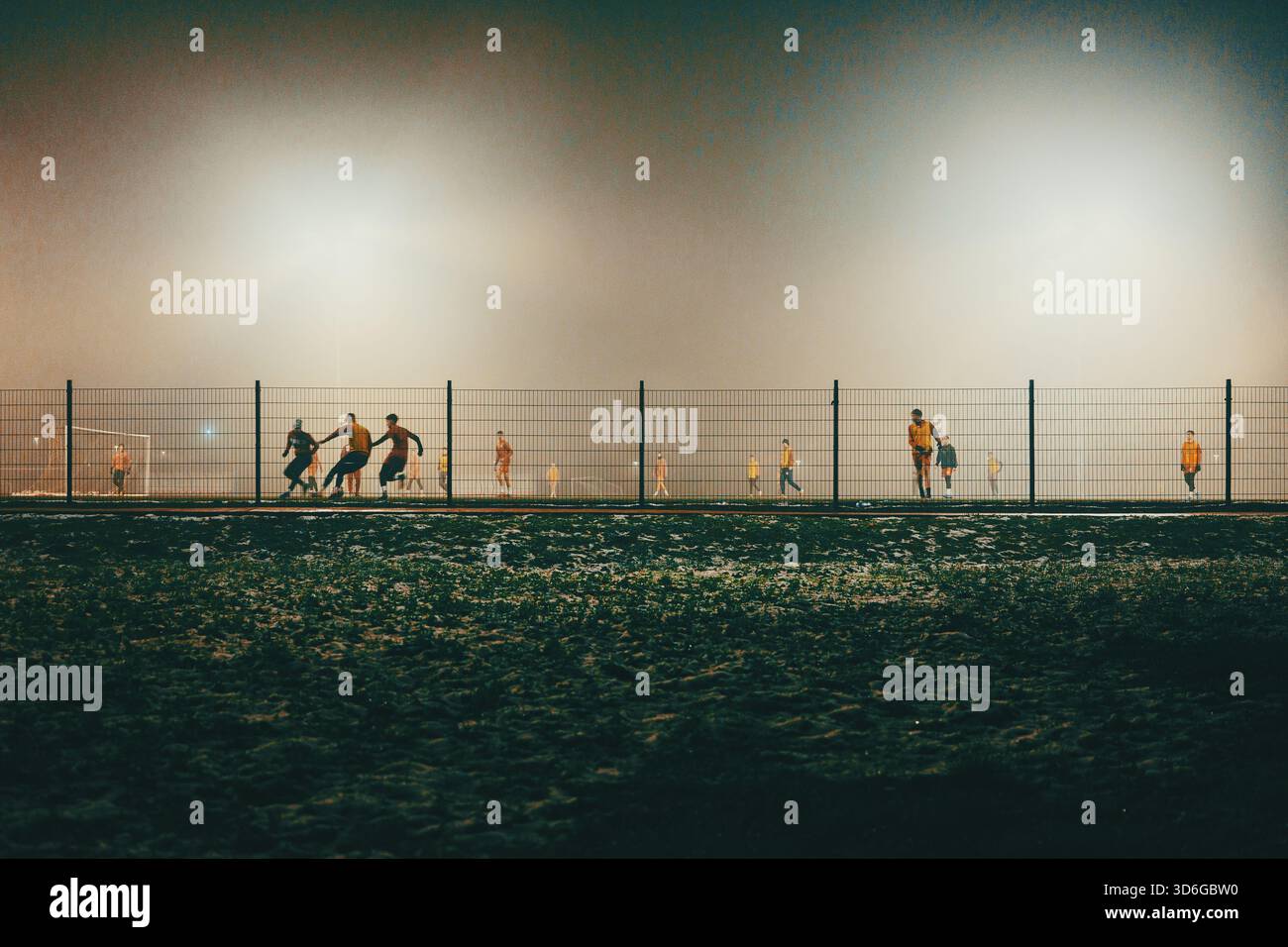 Scena notturna di campi da calcio con giocatori in autunno, atmosfera nebbiosa. Foto Stock