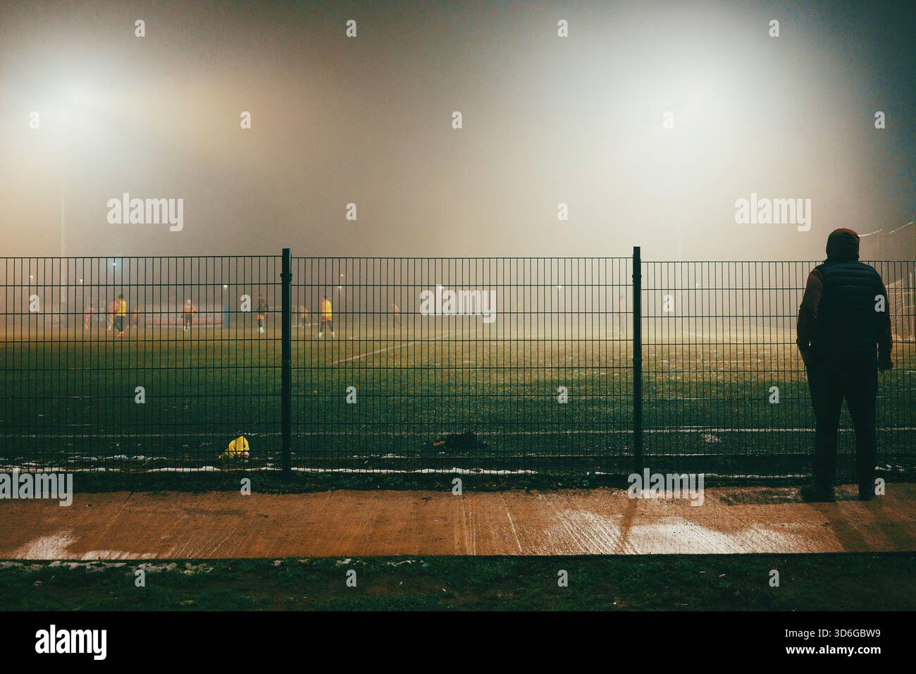 Scena notturna di campi da calcio con giocatori in autunno, atmosfera nebbiosa. Foto Stock