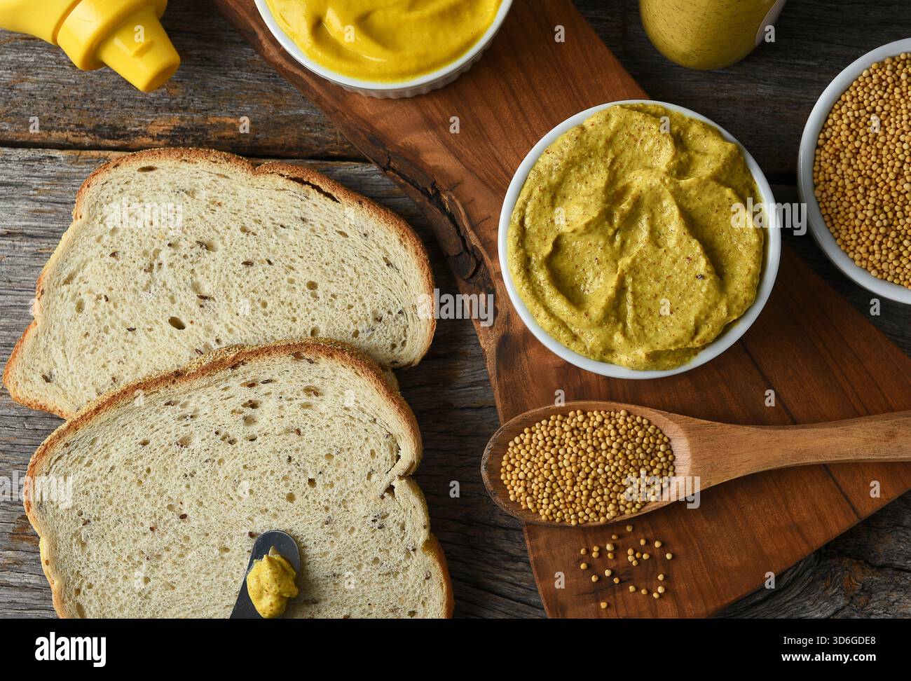 Sandwich con due mostarde diverse in camamolle, pane di segale e semi di senape e bottiglie di senape. Foto Stock