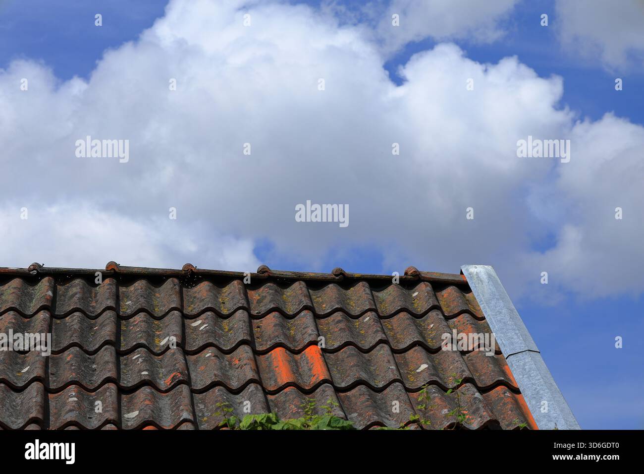 Vecchio tetto piastrellato. Materiale del mattone. Cielo nuvoloso sullo sfondo. Fuori giorno d'estate. Foto Stock