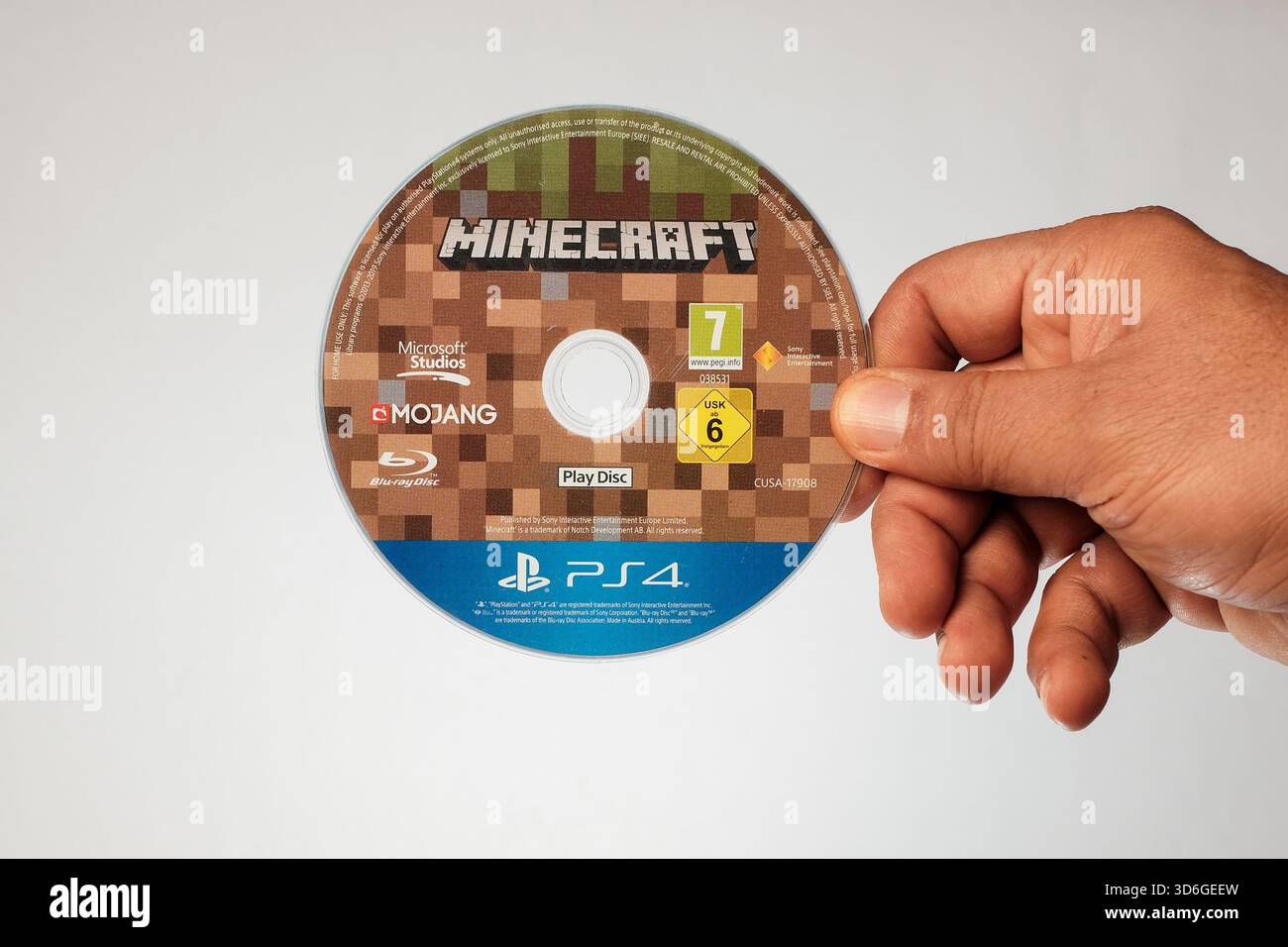 Reggi a mano un disco Blu-ray per PlayStation 4 del popolare gioco sandbox, Minecraft. Foto Stock