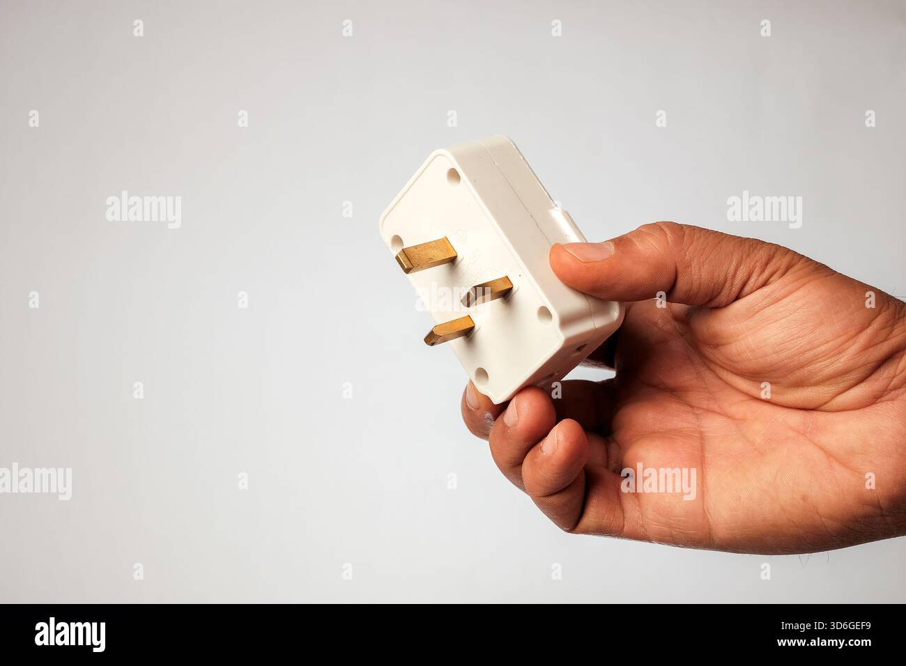 Vista macro di un adattatore da viaggio in plastica bianca progettato per le prese standard del Regno Unito. Foto Stock