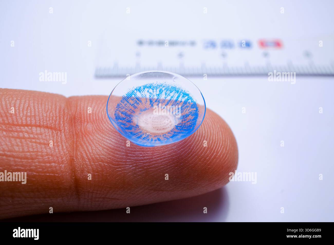 Bassora, Iraq - 5 agosto 2025: Una lente di contatto cosmetica blu appoggiata su un dito Foto Stock