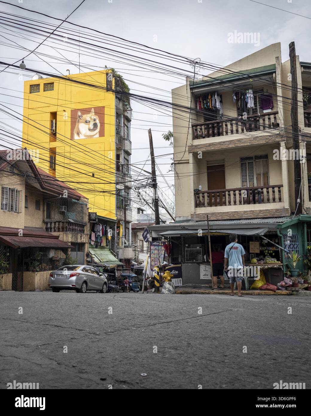 Manila, Filippine - 15 maggio 2023: Veduta di un edificio giallo vibrante con un murale di cani che si innalza sopra la vivace scena stradale, in contrasto con la wea Foto Stock
