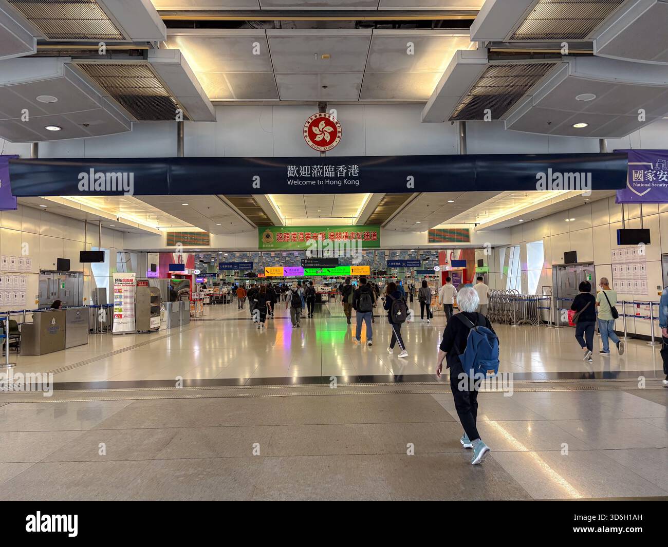 Stazione di controllo Futian che mostra le persone che entrano a Hong Kong da Shenzhen, Cina, sotto un cartello "Welcome to Hong Kong" e l'emblema regionale. Foto Stock