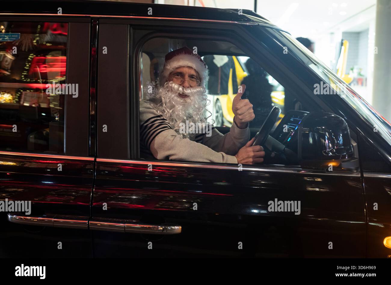 Natale a Londra - Un autista del london Black Cab indossa un cappello di Babbo Natale e la barba mentre era seduto nel suo taxi nel periodo festivo, City of London, Inghilterra, Regno Unito Foto Stock