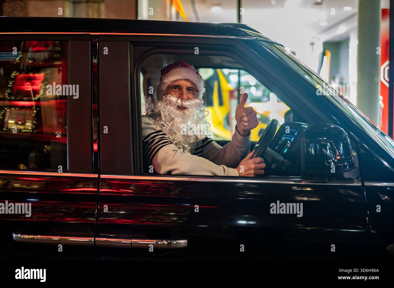 Natale a Londra - Un autista del london Black Cab indossa un cappello di Babbo Natale e la barba mentre era seduto nel suo taxi nel periodo festivo, City of London, Inghilterra, Regno Unito Foto Stock