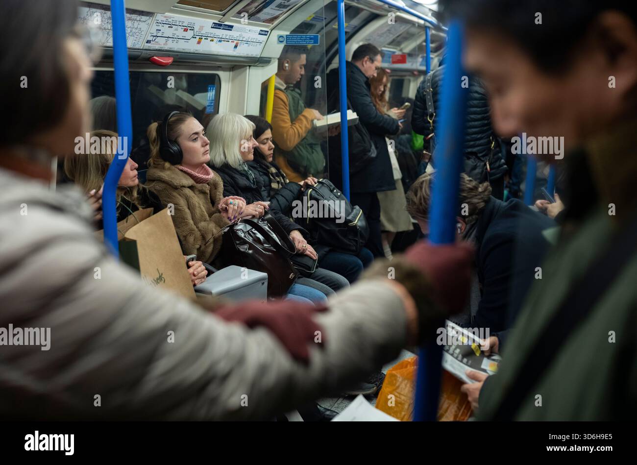 Pendolari e turisti che viaggiano attraverso la capitale su una trafficata carrozza della metropolitana di Londra, nel centro di Londra, Inghilterra, Regno Unito Foto Stock