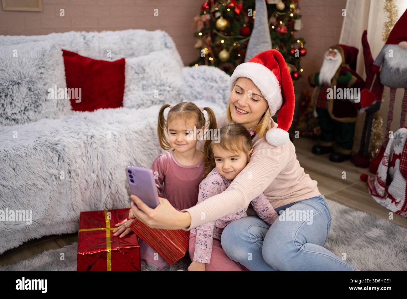 Madre e figlie si fanno selfie vicino all'albero di Natale Foto Stock