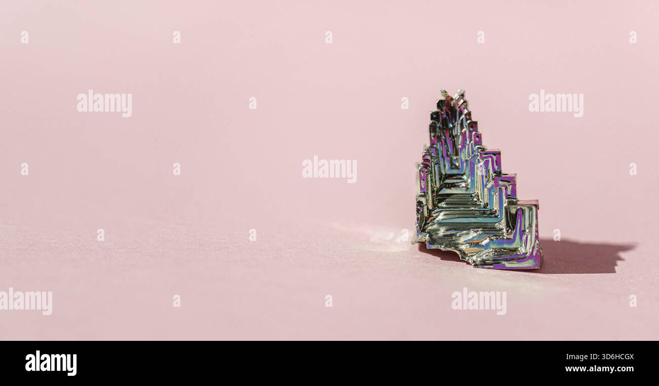 BismuthumCrystal sintetico in bismuto con pellicola di ossido di iridescenza su sfondo rosa primo piano isolato. Incredibile colorata scintillante arcobaleno Bismuth Gemstone mi Foto Stock