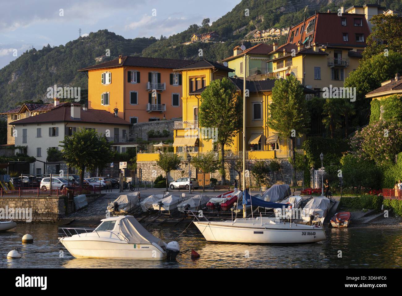 Varenna, Italia - 01.08.2023: Vibrante villaggio sul lago di Varenna, lago di Como, Italia, edifici e barche dai colori vivaci attraccati sul bordo dell'acqua, caldo Foto Stock