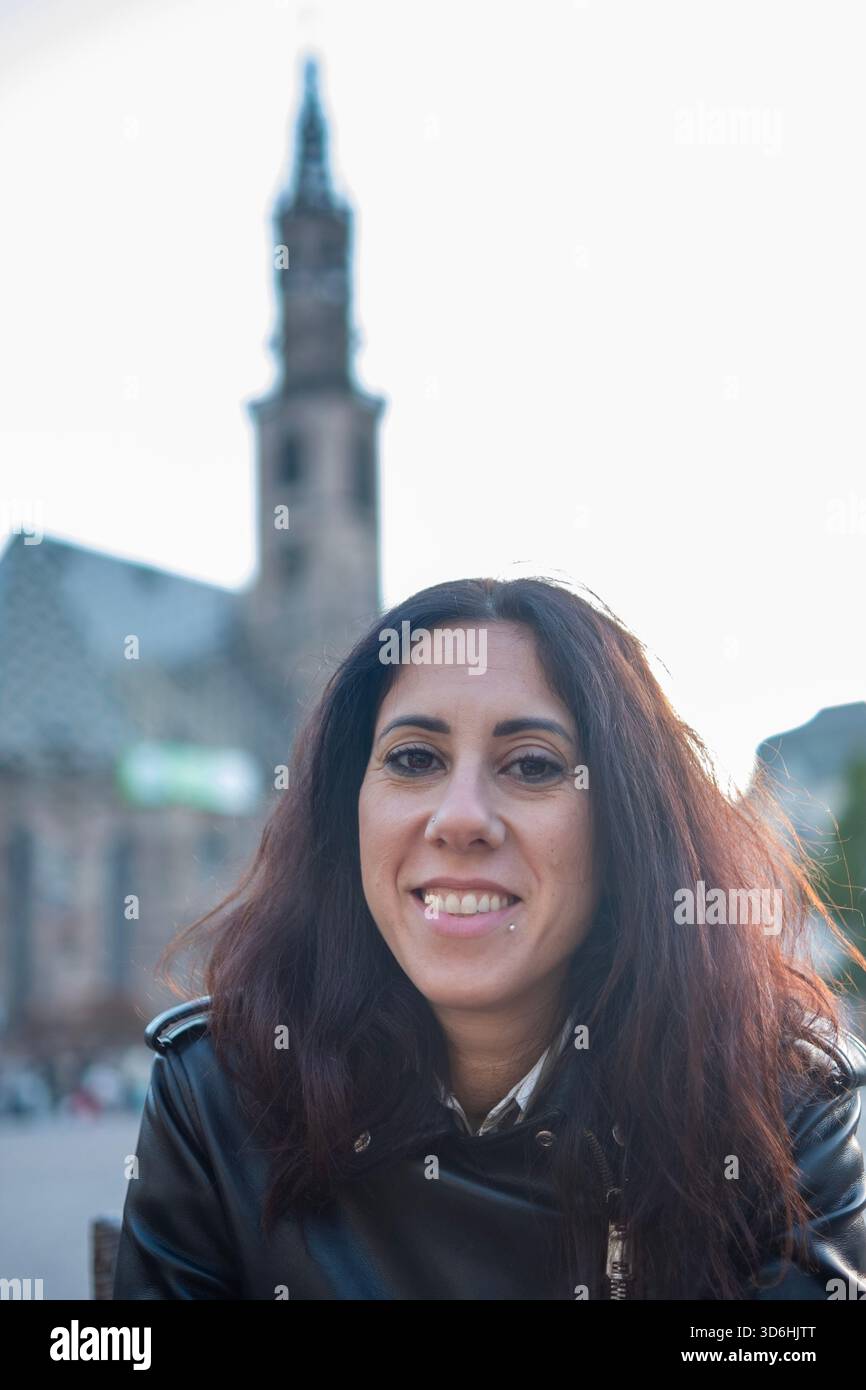 Bella donna dai capelli lunghi nera ritratta in Piazza Walther nel centro storico di Bolzano. La donna ha 39 anni Foto Stock