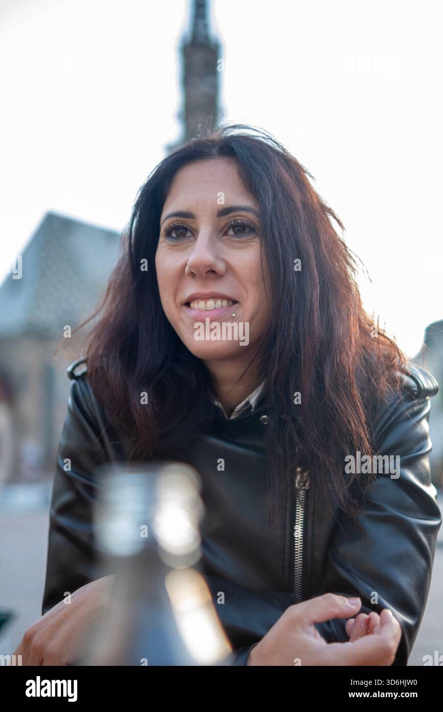 Bella donna dai capelli lunghi nera ritratta in Piazza Walther nel centro storico di Bolzano. La donna ha 39 anni Foto Stock