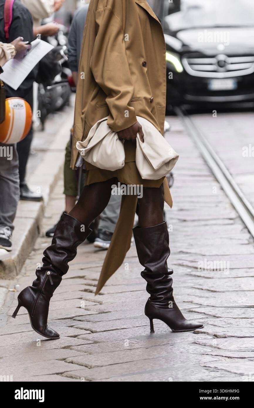 Milano, Italia - 21 settembre 2022: Donne alla moda che indossano camice marrone, gonna coordinata e crop top, stivali in pelle con tacco alto marrone, beige tenente Foto Stock