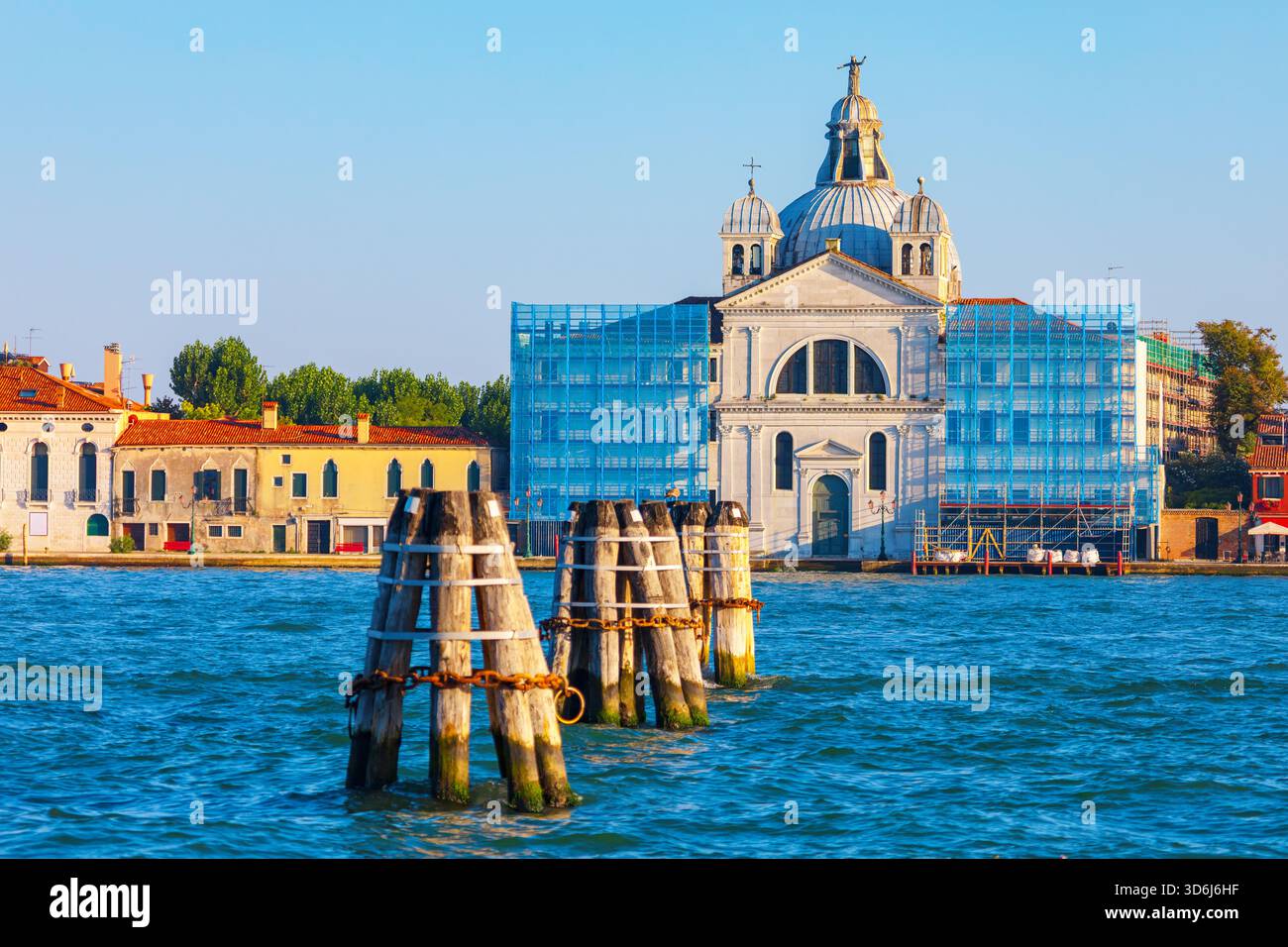 La Chiesa delle Zitelle sull'isola della Giudecca, Venezia, si erge ben oltre il canale, parzialmente oscurata da impalcature blu che indicano riparazioni Foto Stock