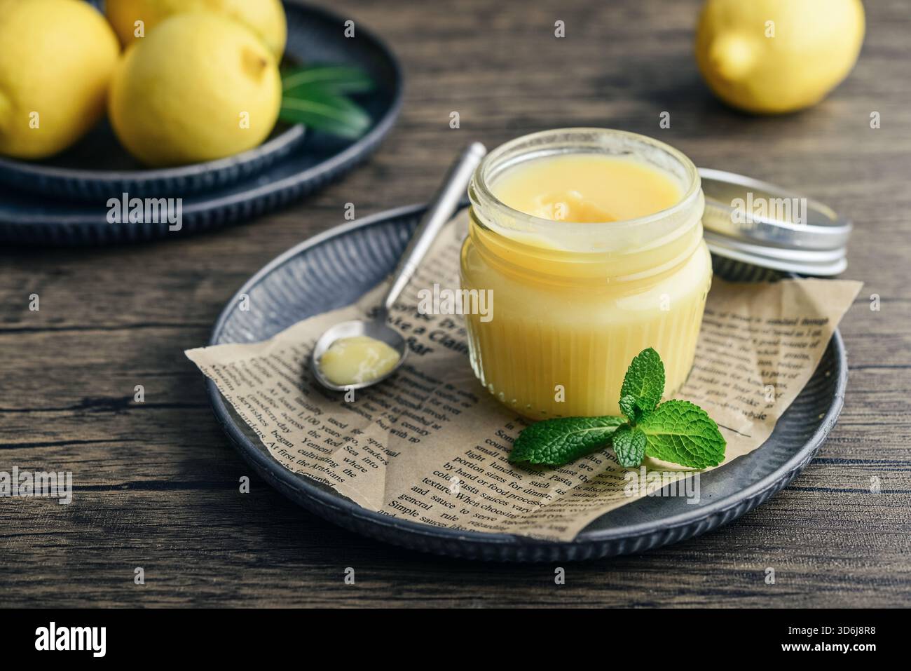 Cagliata di limone fatta in casa in un vaso di vetro con foglie di menta e limoni freschi su fondo di legno Foto Stock
