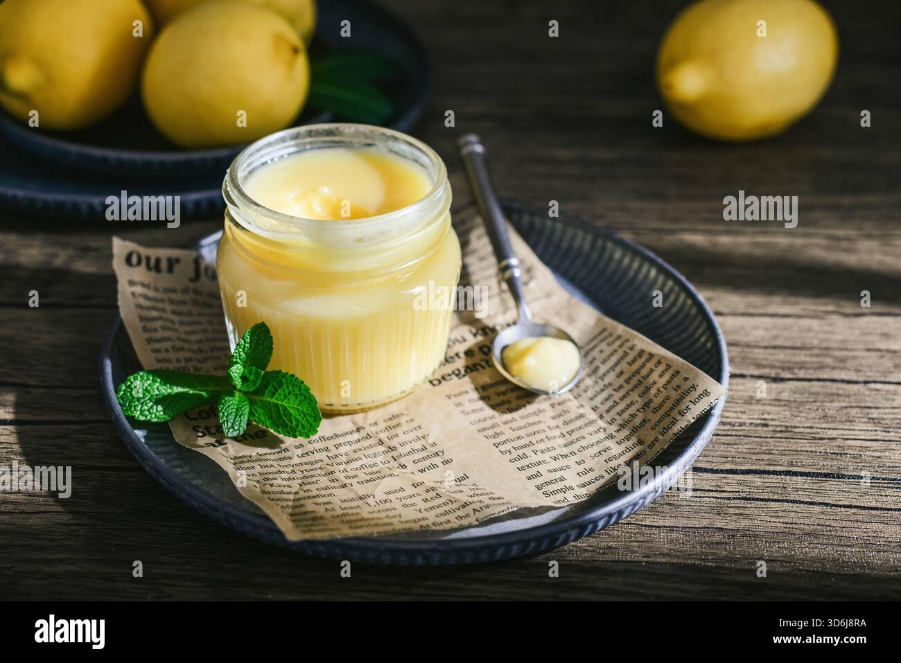 Cagliata di limone fatta in casa in un vaso di vetro con foglie di menta e limoni freschi su fondo di legno Foto Stock