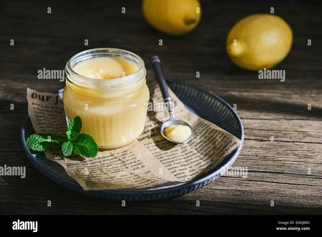 Cagliata di limone fatta in casa in un vaso di vetro con foglie di menta e limoni freschi su fondo di legno Foto Stock