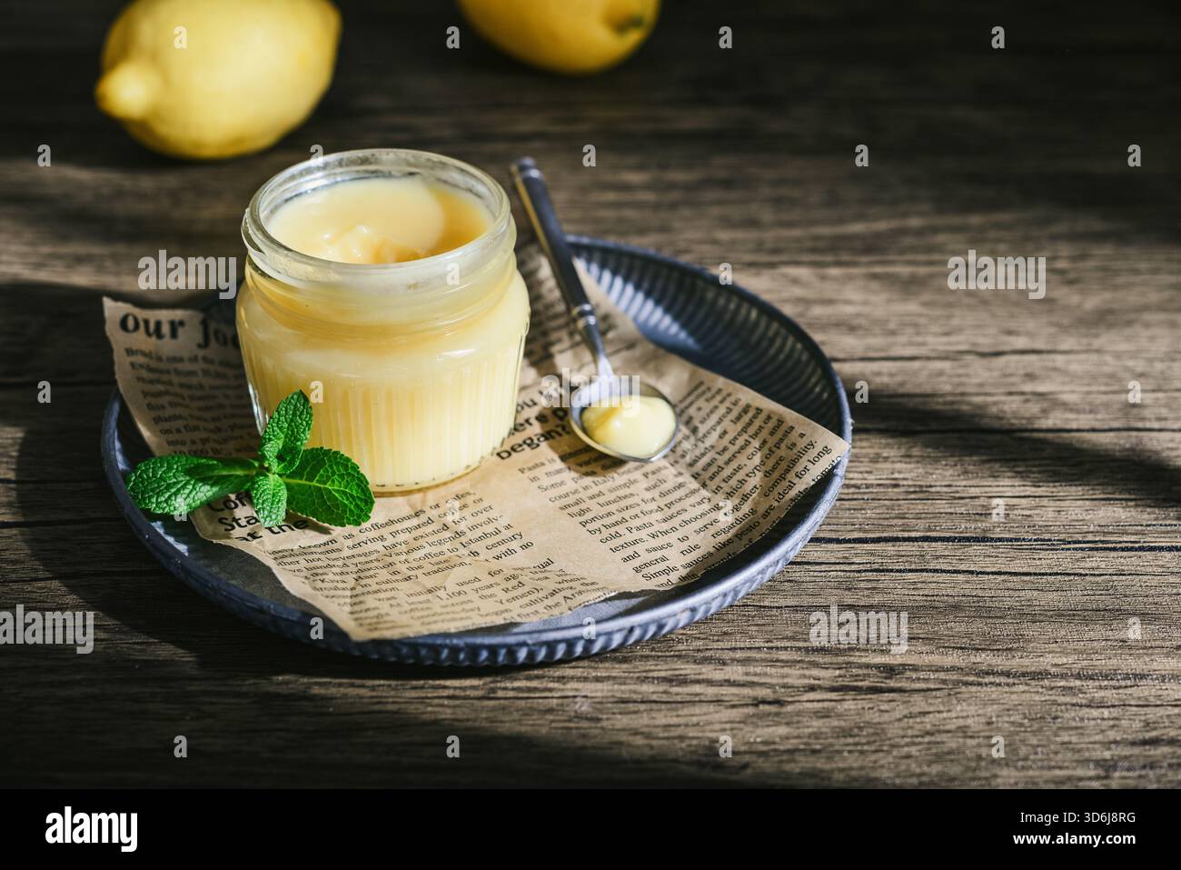 Cagliata di limone fatta in casa in un vaso di vetro con foglie di menta e limoni freschi su fondo di legno Foto Stock