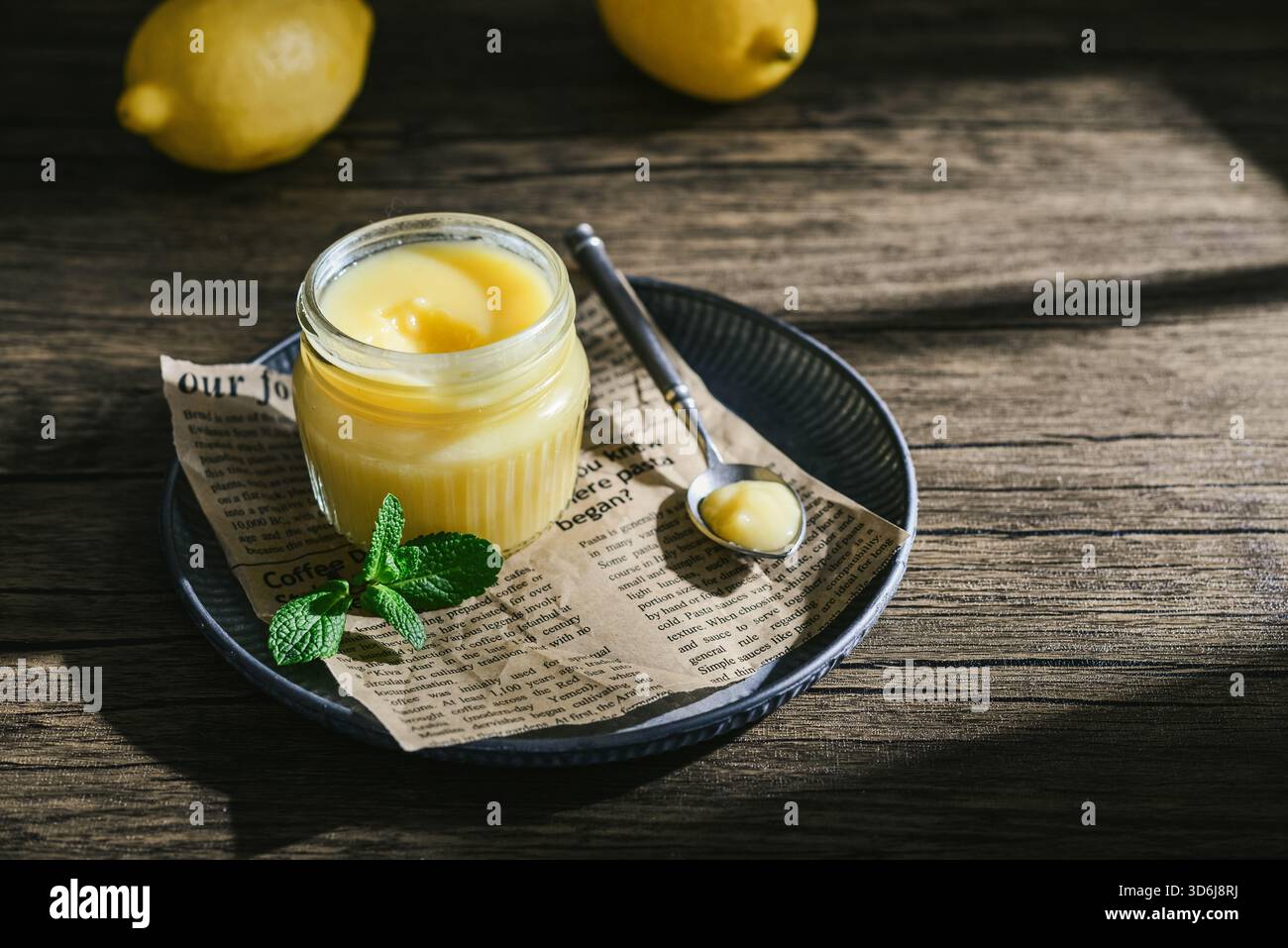 Cagliata di limone fatta in casa in un vaso di vetro con foglie di menta e limoni freschi su fondo di legno Foto Stock