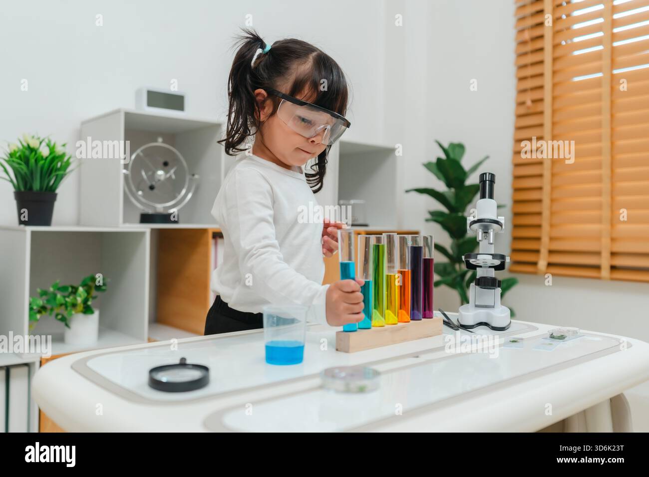 scienziata felice che impara la scienza con il tubo di prova e un bicchiere Foto Stock