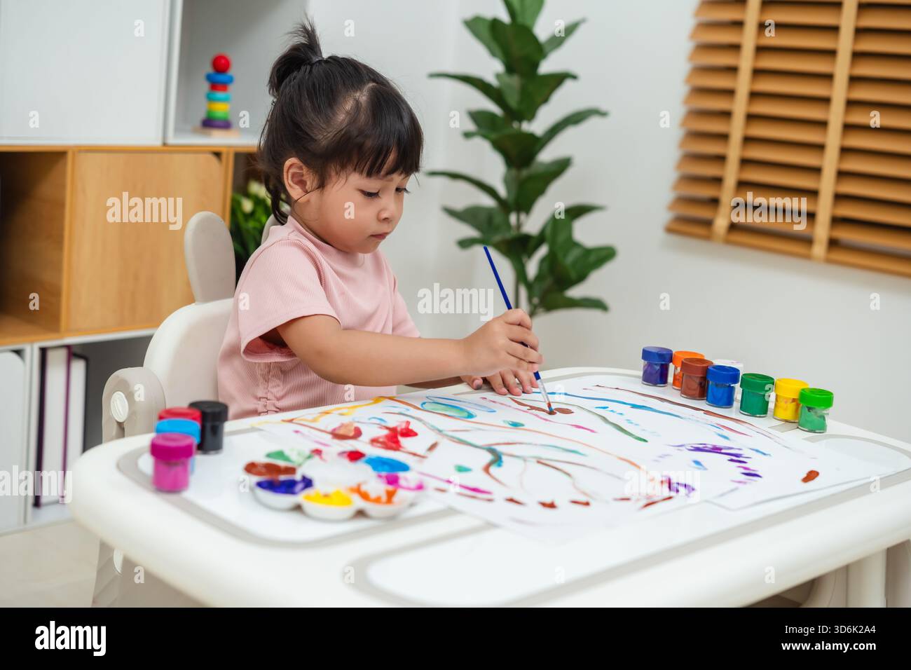 felice bambina che dipinge l'acquerello in un giornale a casa Foto Stock