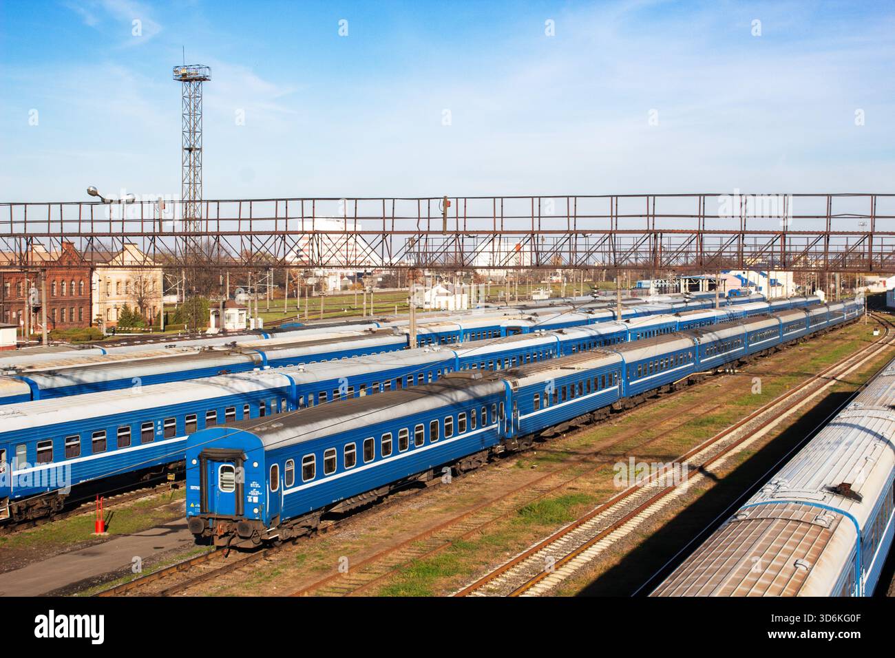 Vista aerea delle carrozze blu dei treni passeggeri in piedi su più binari ferroviari in un deposito ferroviario in una giornata di sole limpido. Foto Stock