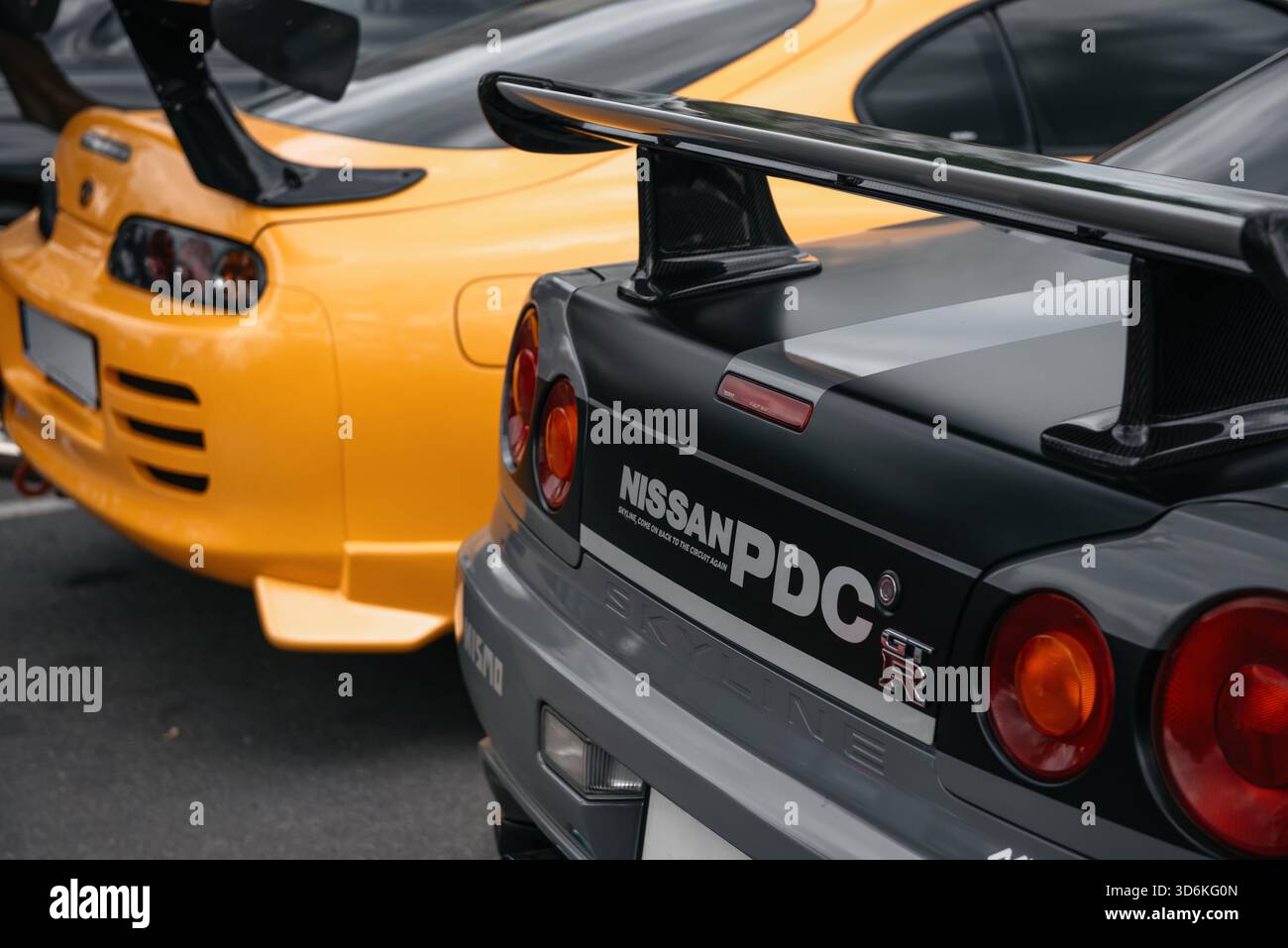 JDM CAR Meet - i proprietari di auto giapponesi si radunano - parte posteriore della Toyota Supra gialla e della Nissan Skyline GT-R grigia parcheggiate fianco a fianco. Foto Stock