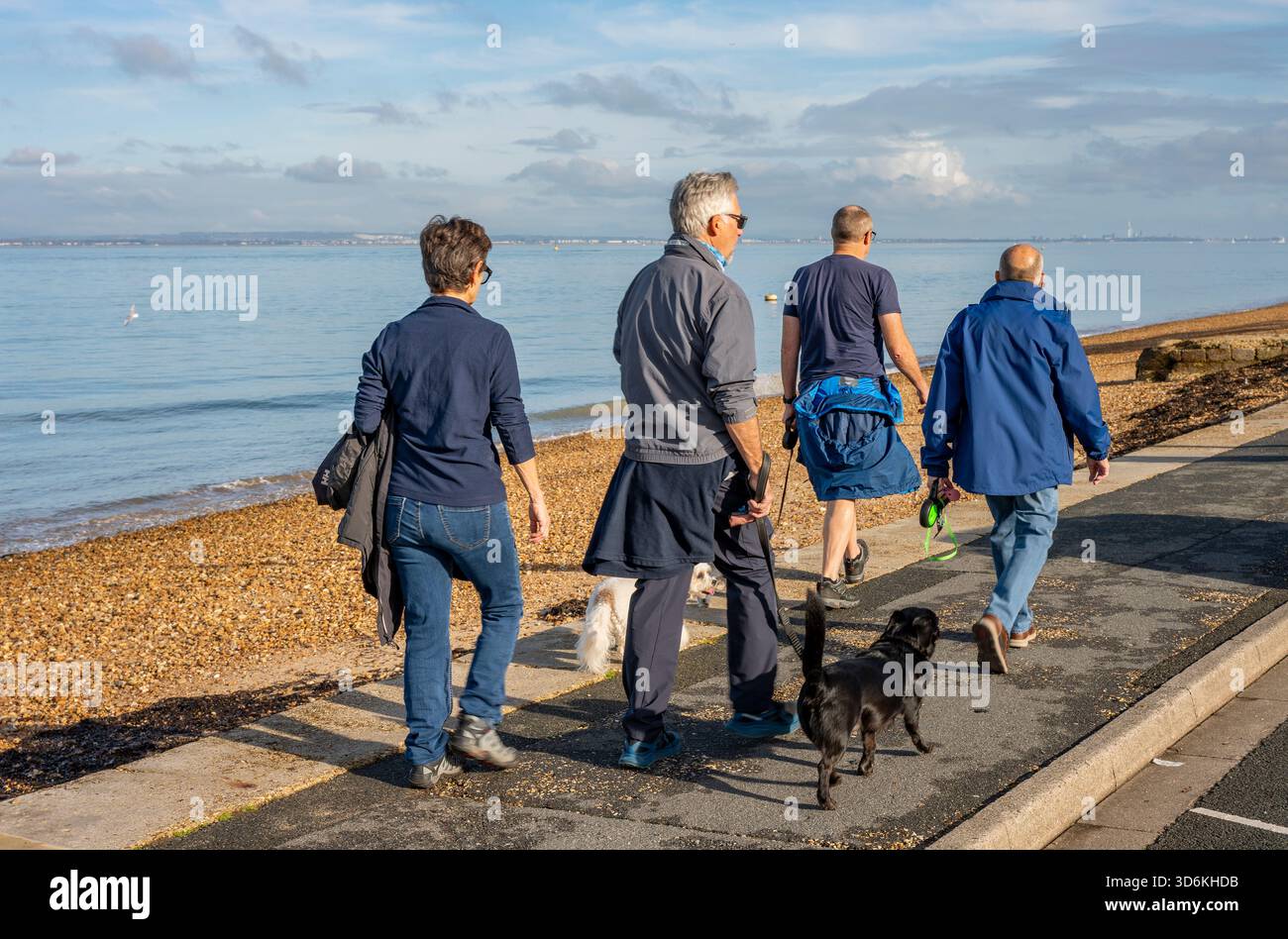 Persone che camminano lungo il lungomare di Cowes, sulla costa dell'isola di wight. Una coppia che cammina con un piccolo cane al mare. Foto Stock