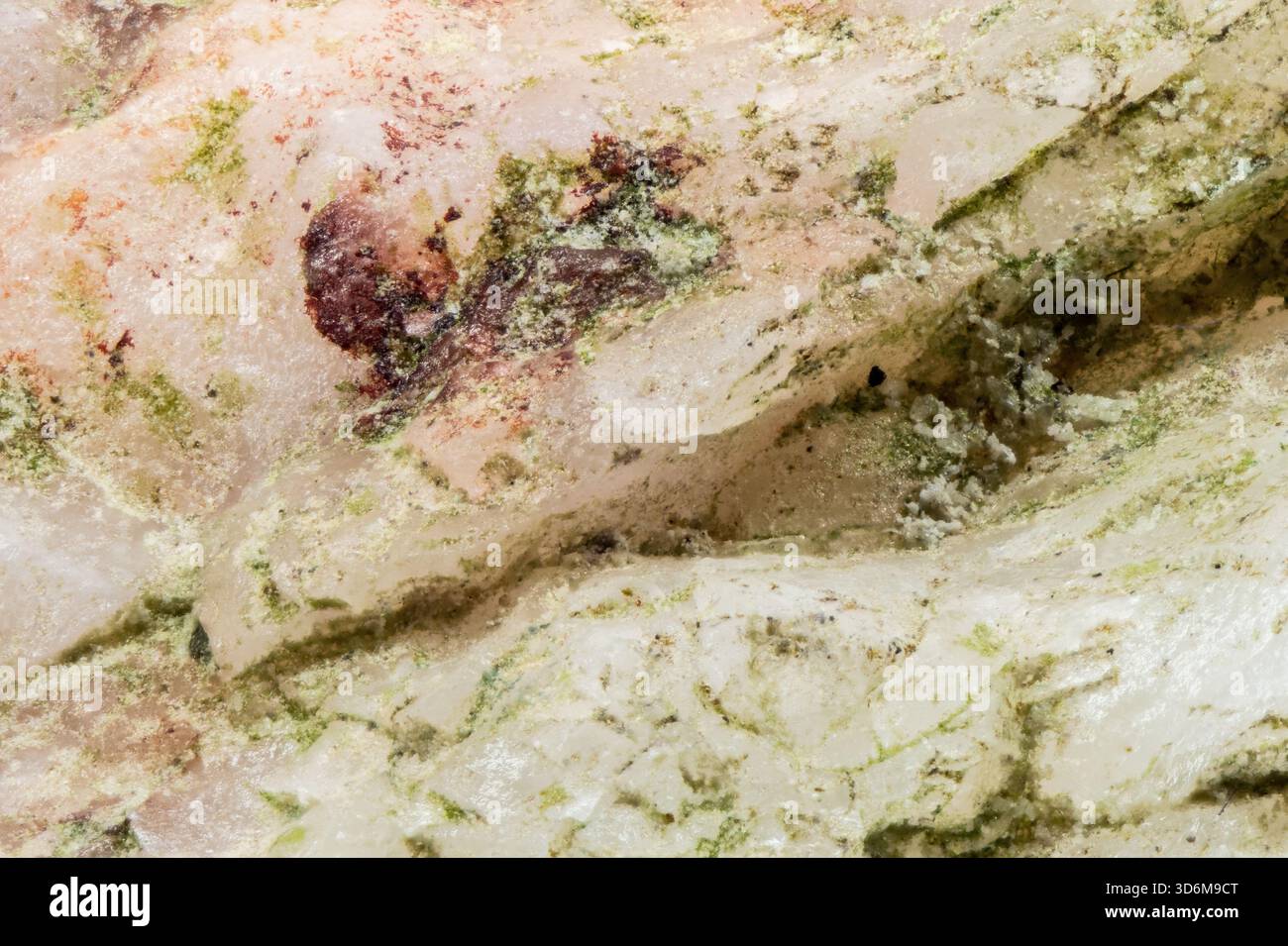 Primo piano di pietra di marmo bianco con venature minerali verdi e inclusioni rossastre Foto Stock