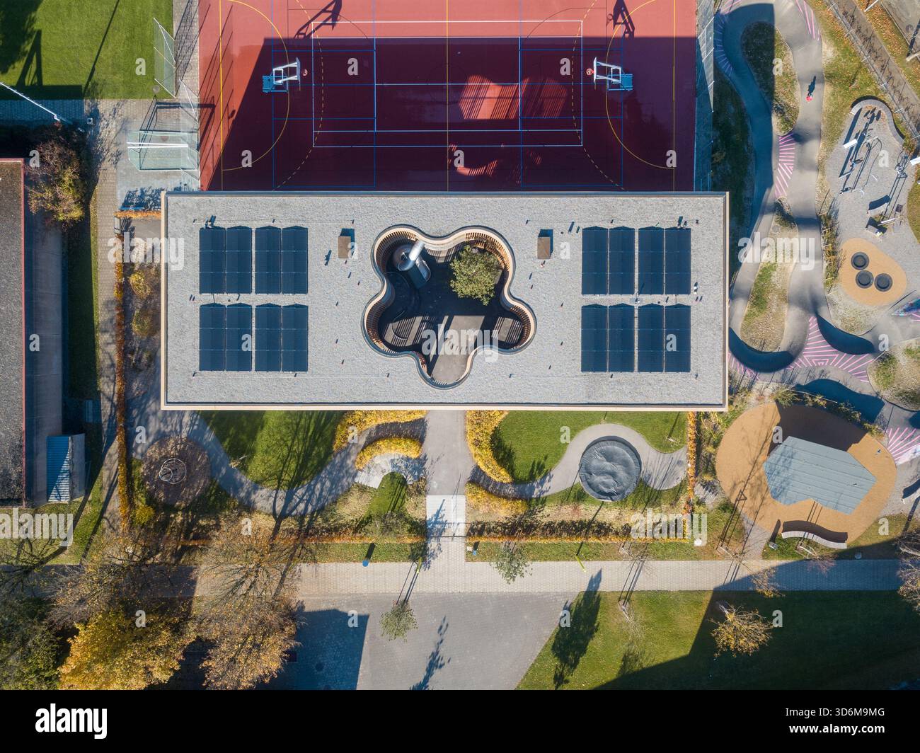 Vista aerea dell'asilo di Ittigen con cortile sul tetto, pannelli solari e parco giochi colorato Foto Stock