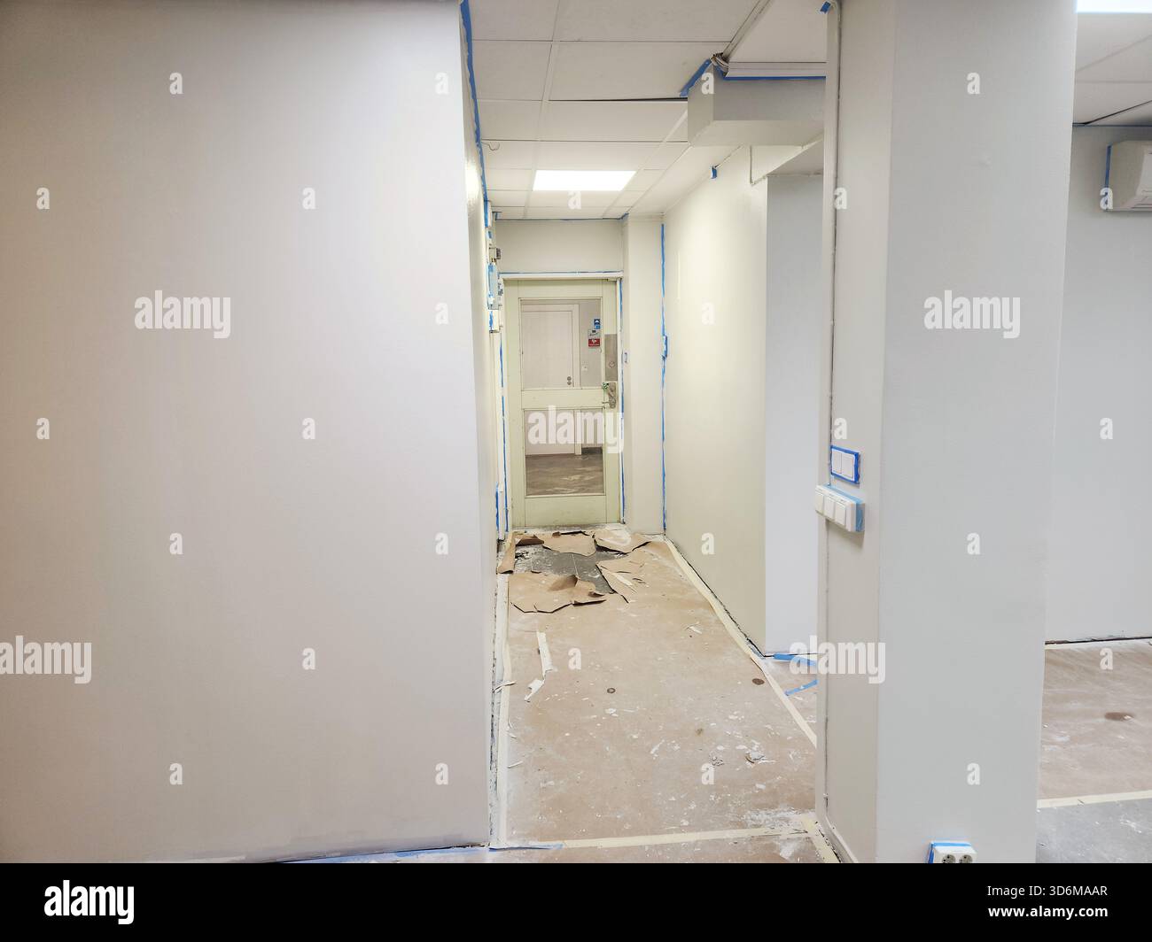 Vista ravvicinata del corridoio stretto durante i lavori di ristrutturazione con pareti beige e pavimento ricoperto di carta protettiva. Svezia. Stoccolma. Foto Stock