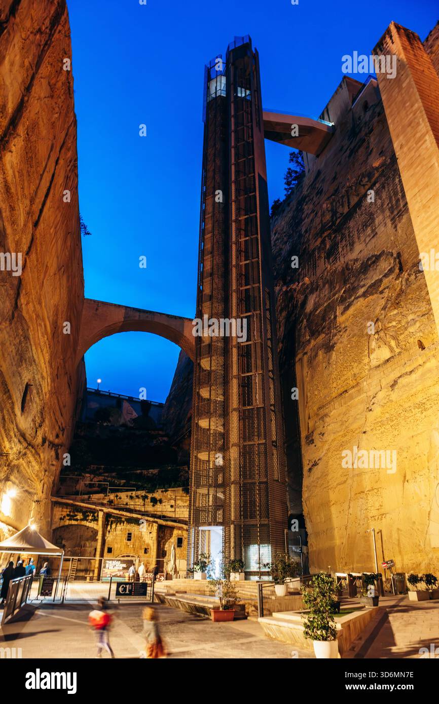 La Valletta, Malta? 13 aprile 2025: Vista notturna dell'ascensore Barrakka, un moderno ascensore panoramico costruito all'interno di bastioni storici, che collega il lungomare di Grand Harbour al centro della città Foto Stock