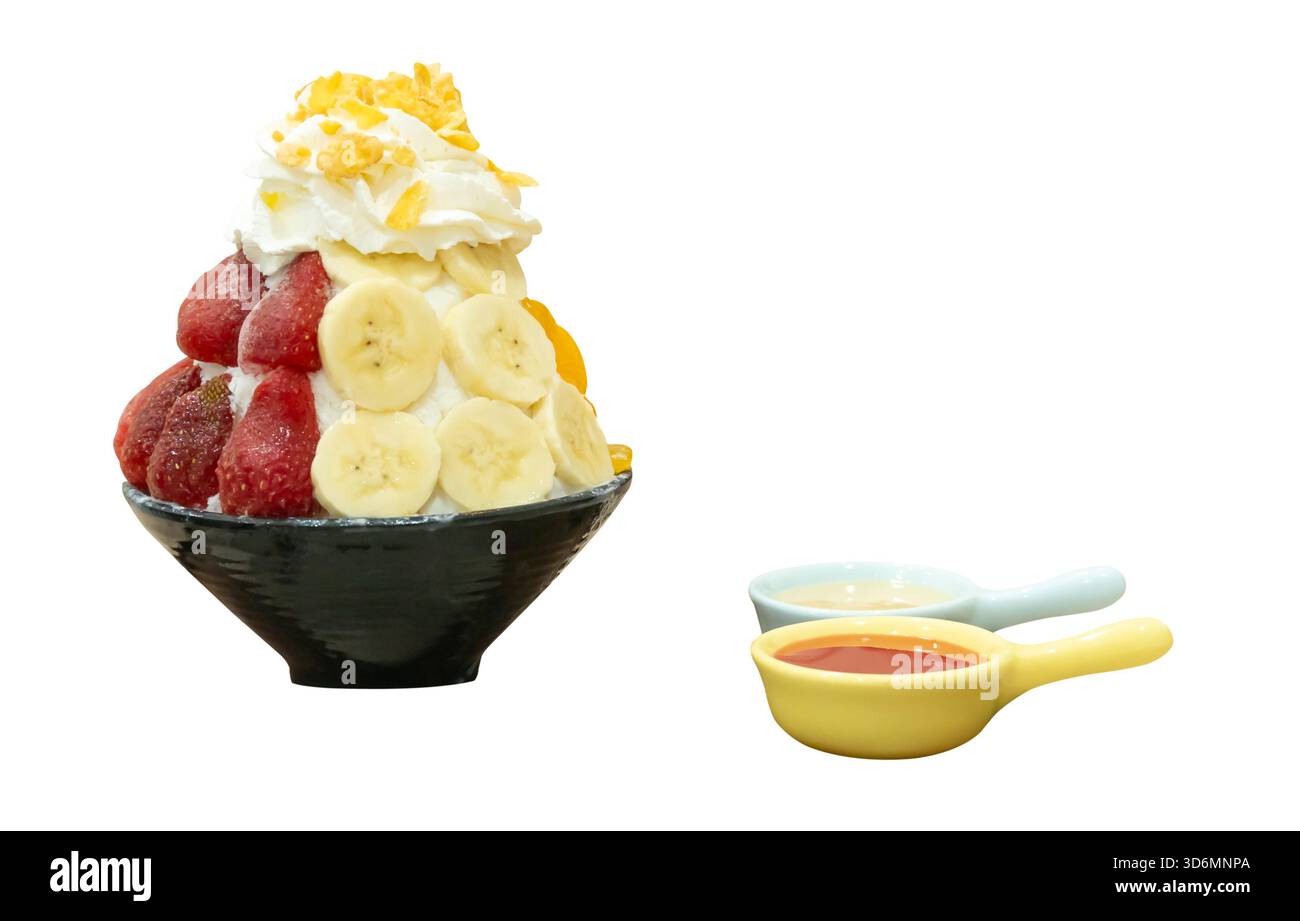 Un set di Bingsu coreano in una piccola ciotola nera con diversi condimenti di frutta e salsa rossa con latte condensato dolce in piccoli cucchiai sono isolati su bianco Foto Stock
