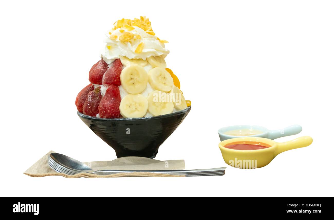 Un set di Bingsu coreano in una piccola ciotola nera con diversi condimenti di frutta e salsa rossa con latte condensato dolce in mini ciotole di plastica sono isolati su Foto Stock