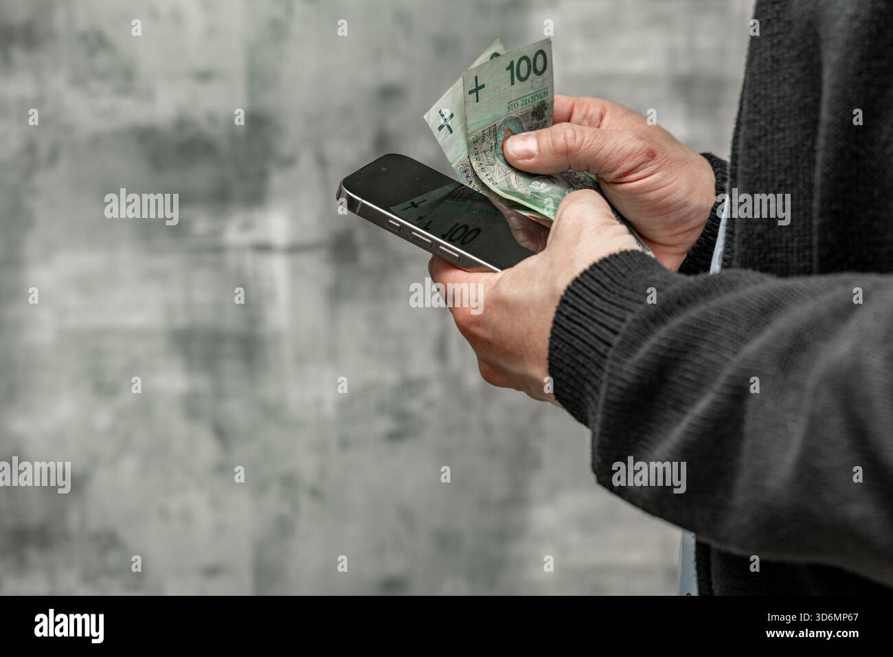 Un uomo con una camicia blu e un maglione tiene i soldi in mano, contando i soldi prima di spenderli. Foto Stock