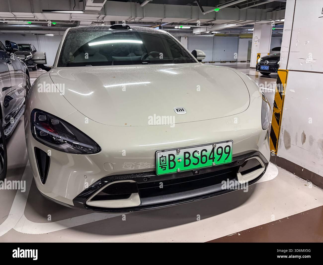 Vista frontale di una berlina elettrica Xiaomi SU7 color crema, con il suo logo distintivo e una targa verde cinese EV (粤B) da Shenzhen, chi Foto Stock