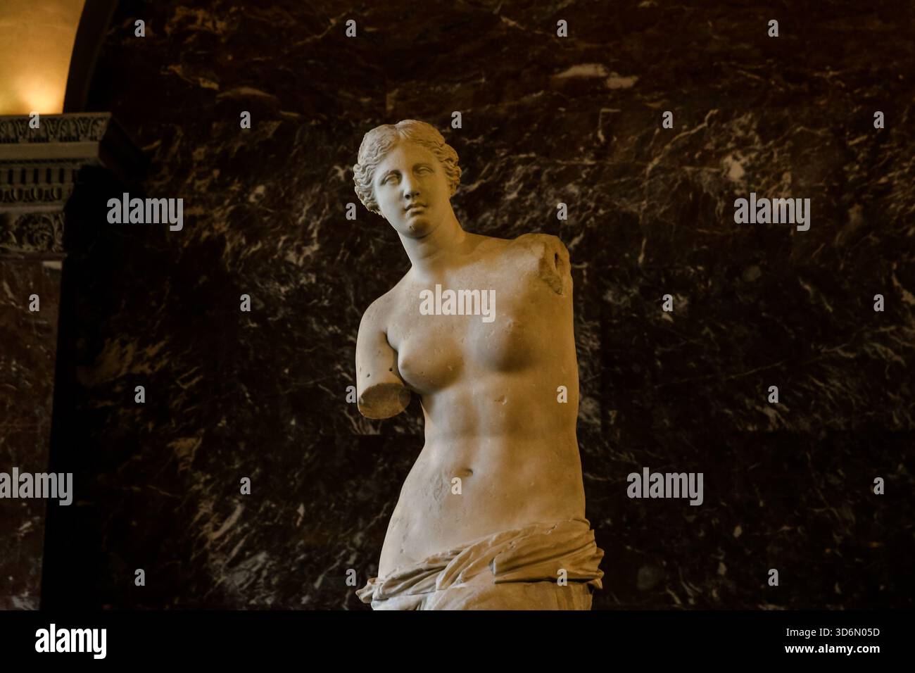 L'antica statua greca Venere di Milo esposta nel Museo del Louvre di Parigi, esposta su uno sfondo di marmo scuro nella galleria di sculture. Foto Stock