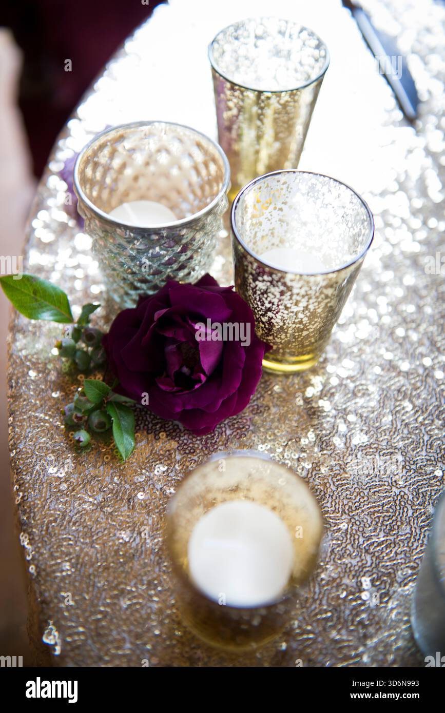 Rosa viola intenso con candele votive su tovaglia di paillettes Foto Stock