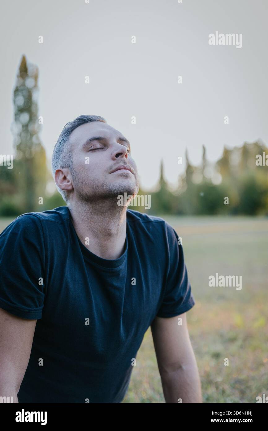 Ritratto di un uomo che pratica respirazione profonda e meditazione all'aperto nel parco autunnale. Foto Stock