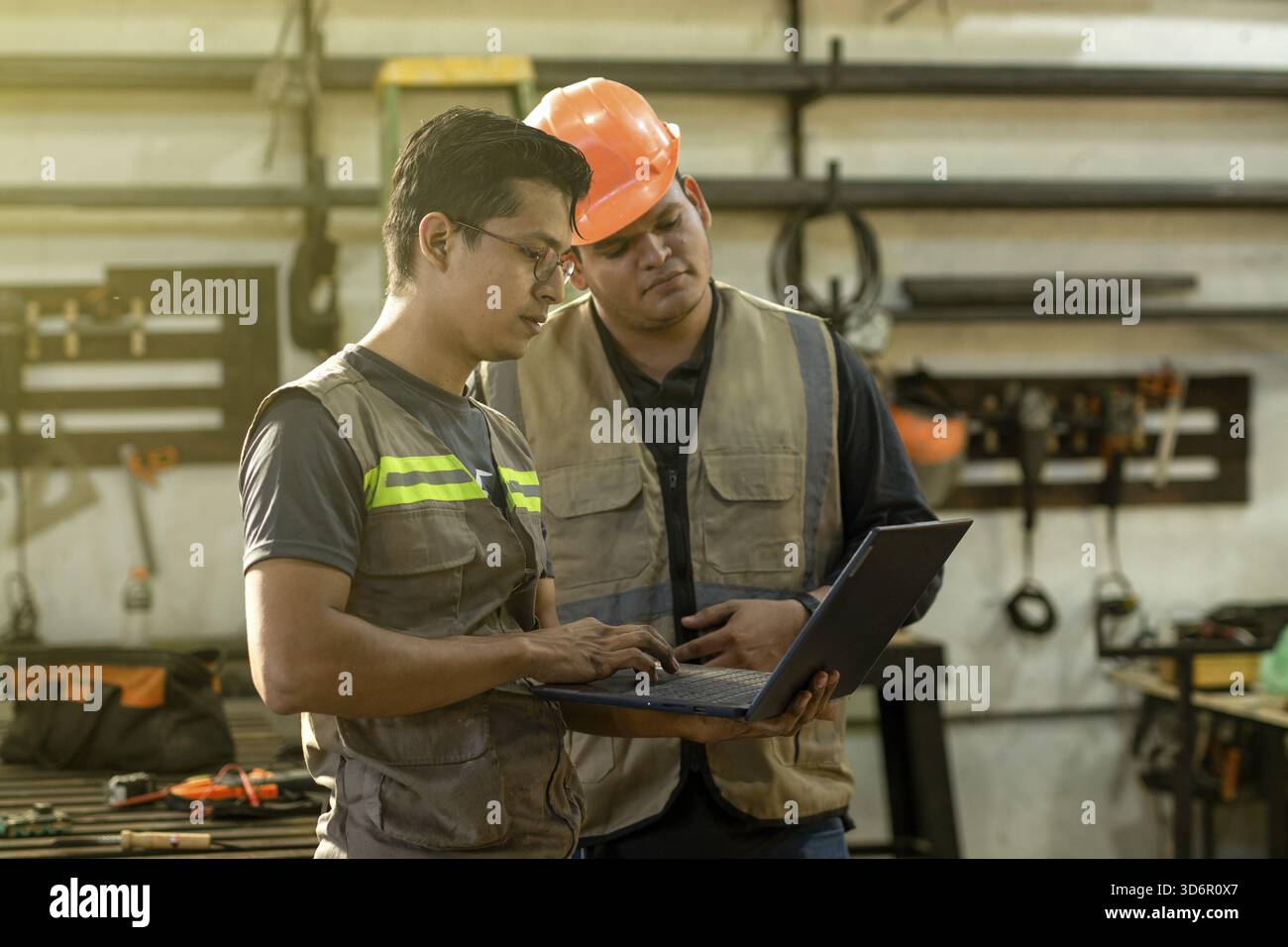 Responsabile dell'officina di falegnameria che utilizza il computer per insegnare a un lavoratore. Caposquadra della falegnameria che mostra il computer al collega in officina Foto Stock