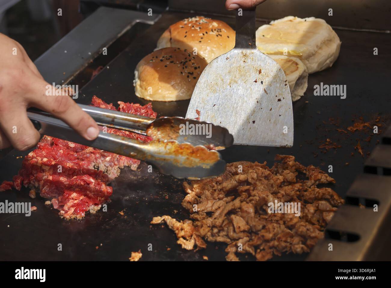 Piatti caldi a base di carne e formaggio. lo chef prepara manzo salato e tosta il pane per un appetitoso sandwich, un fantastico pasto fresco Foto Stock