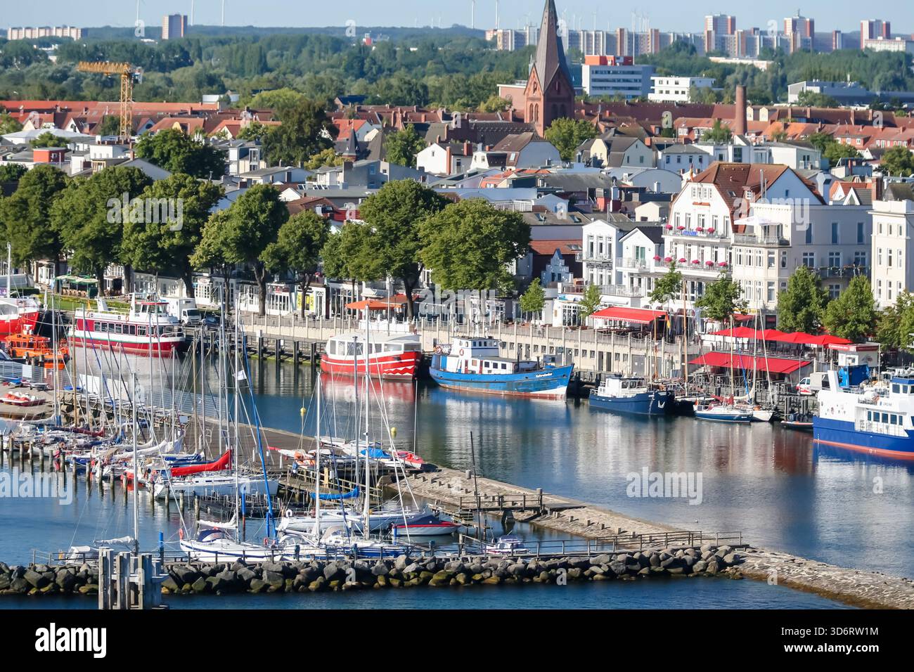 Barche e yacht colorati ormeggiati lungo il porticciolo di Rostock, con la storica città vecchia e il lungomare dietro. Foto Stock