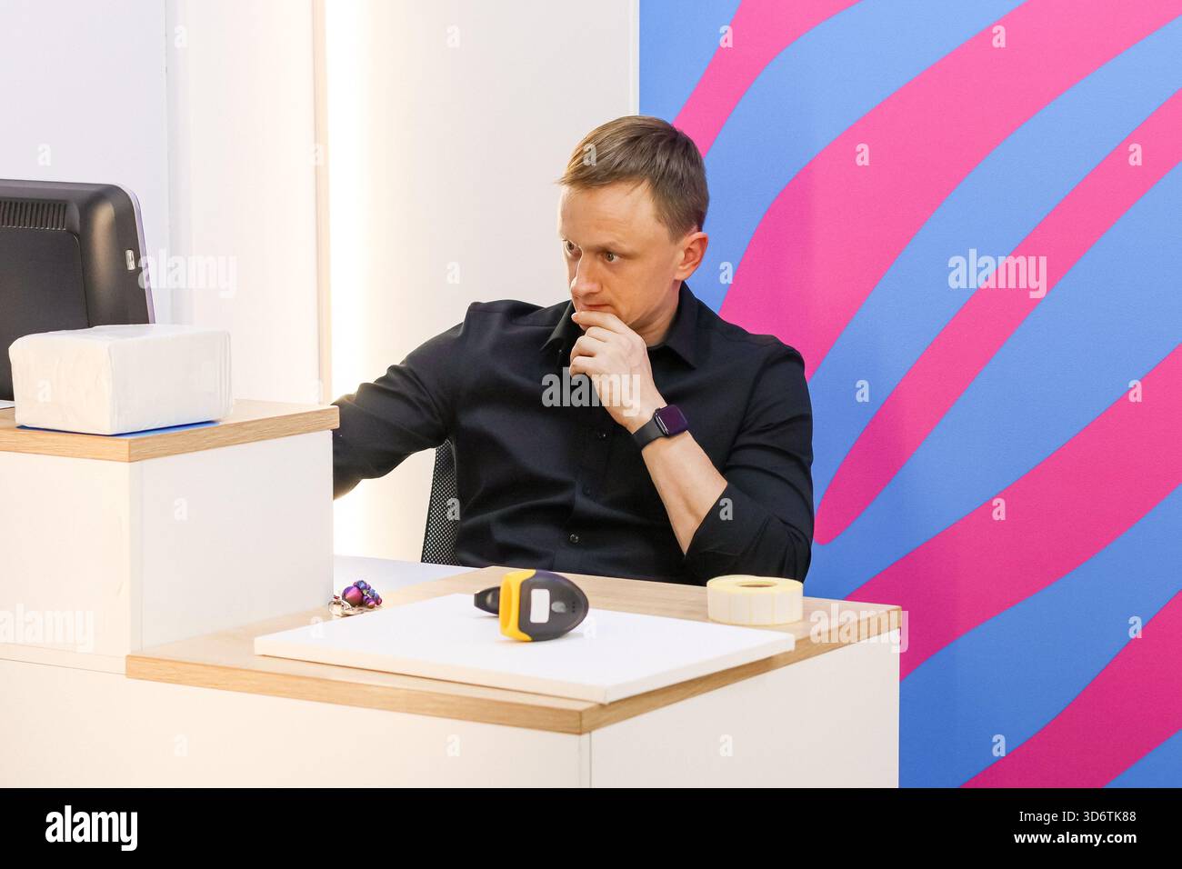 Vista laterale del lavoratore con la mano sul mento alla scrivania con strumenti su uno sfondo vivace Foto Stock