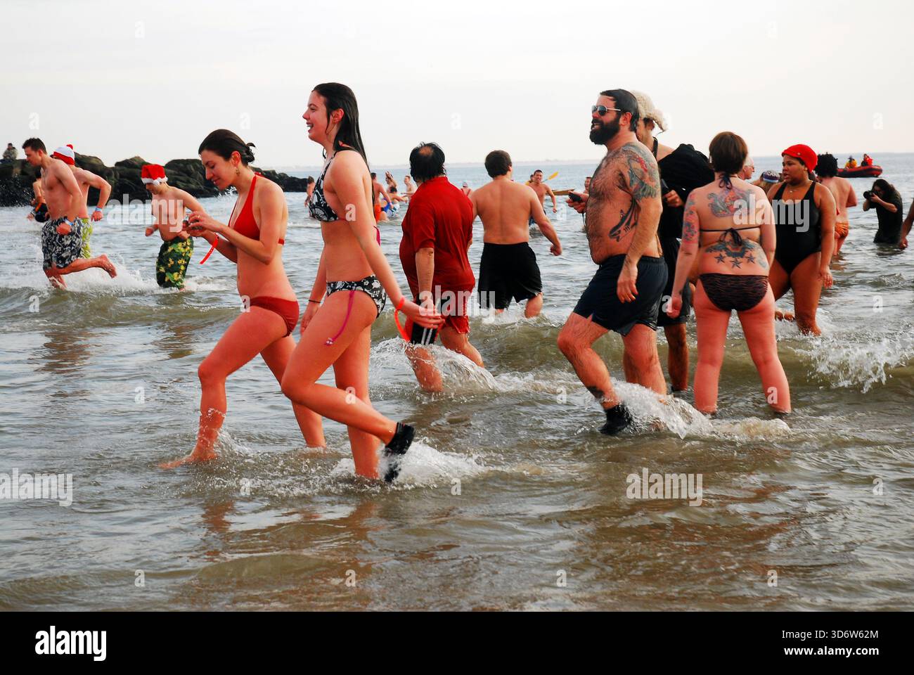 Un gruppo di persone torna in spiaggia durante l'annuale tuffo nell'orso polare di Capodanno in una giornata invernale a Coney Island Foto Stock
